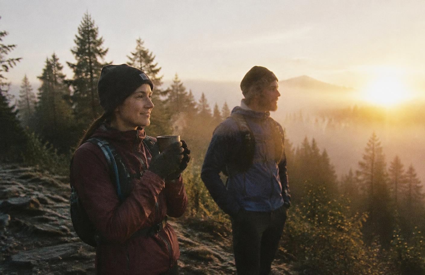 Coureurs trail arrêtés à l'aube, tasse de café fumante à la main